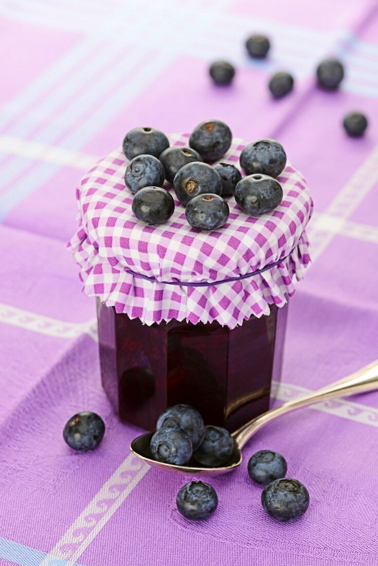 Heidelbeermarmelade mit frischen Heidelbeeren und einem Löffel