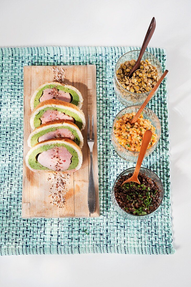 Pork fillet wrapped in bread and herbs on a bed of colourful lentils