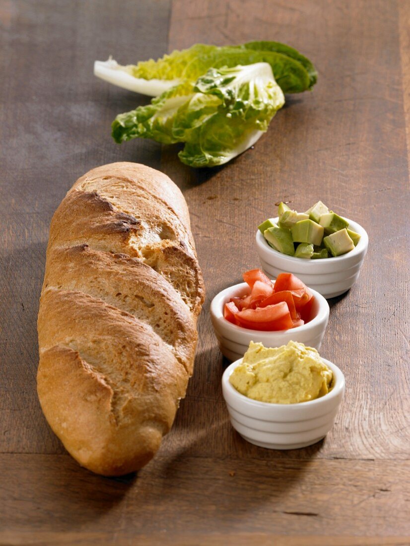 Ingredients for a baguette with an avocado dip (bread, curry dip, tomatoes, avocado and lettuce)