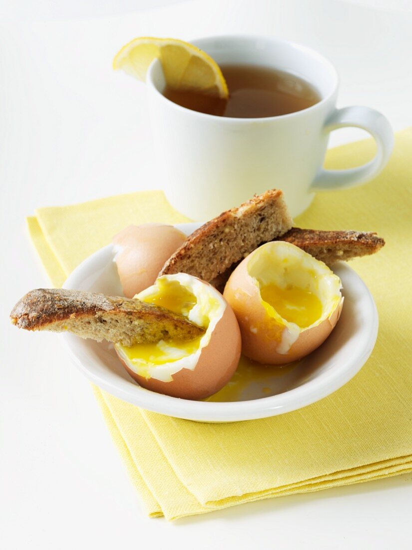 Frühstück mit weichen Eiern, Brotsticks und Schwarztee