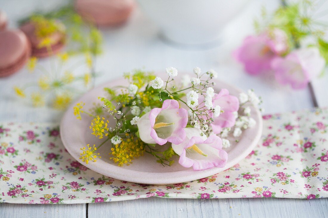 Bell flowers and baby's breath and fennel flowers on a light pink plate