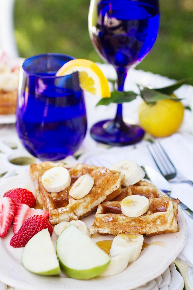 Belgian Waffles with Syrup and Fresh Fruit on an Outdoor Table
