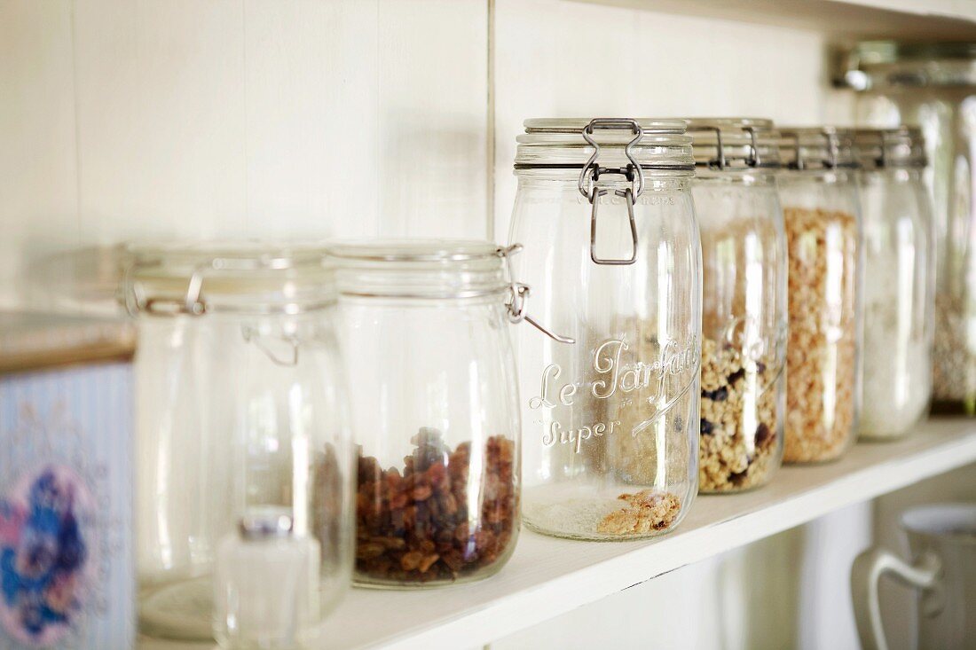 Verschiedene Trockenfrüchte und Cerealien in Vorratsgläsern auf Küchenboard