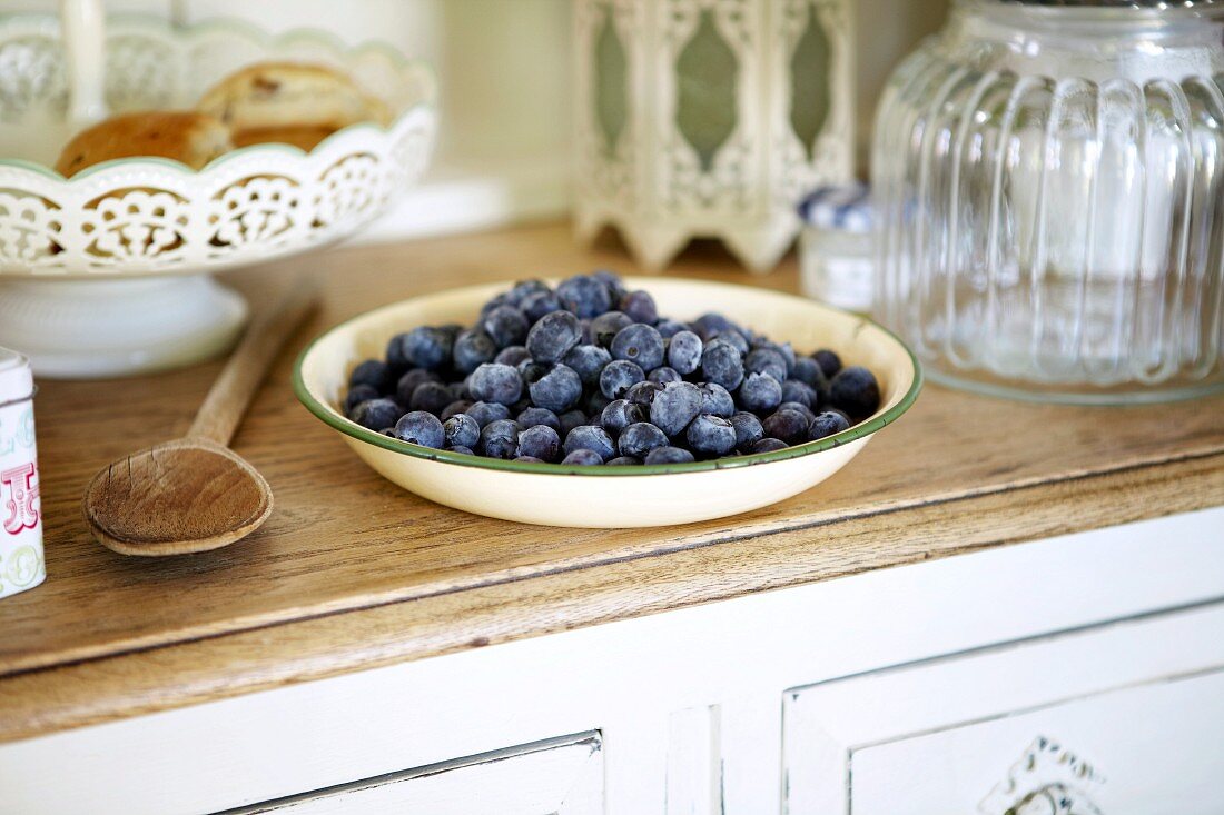 A bowl of blueberries on a kitchen dresser