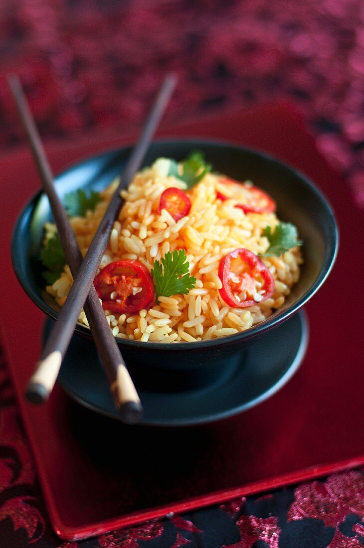 A bowl of turmeric rice with chilli rings and coriander