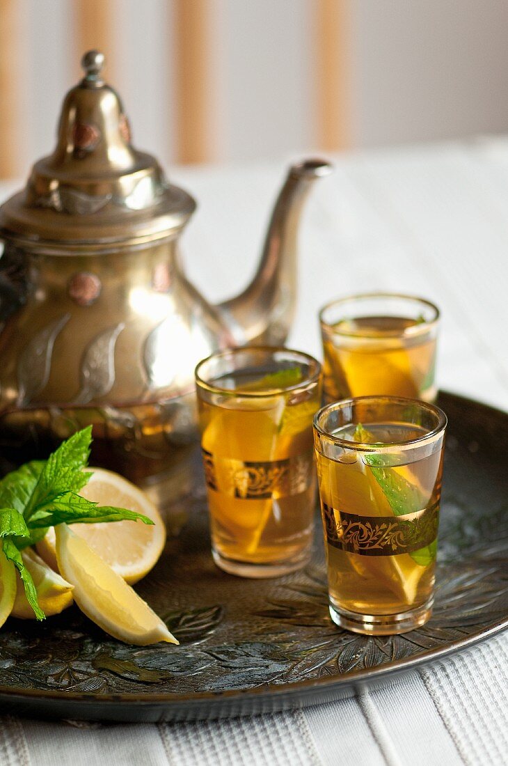 Tee mit Minze und Zitrone in drei Gläsern und Teekanne