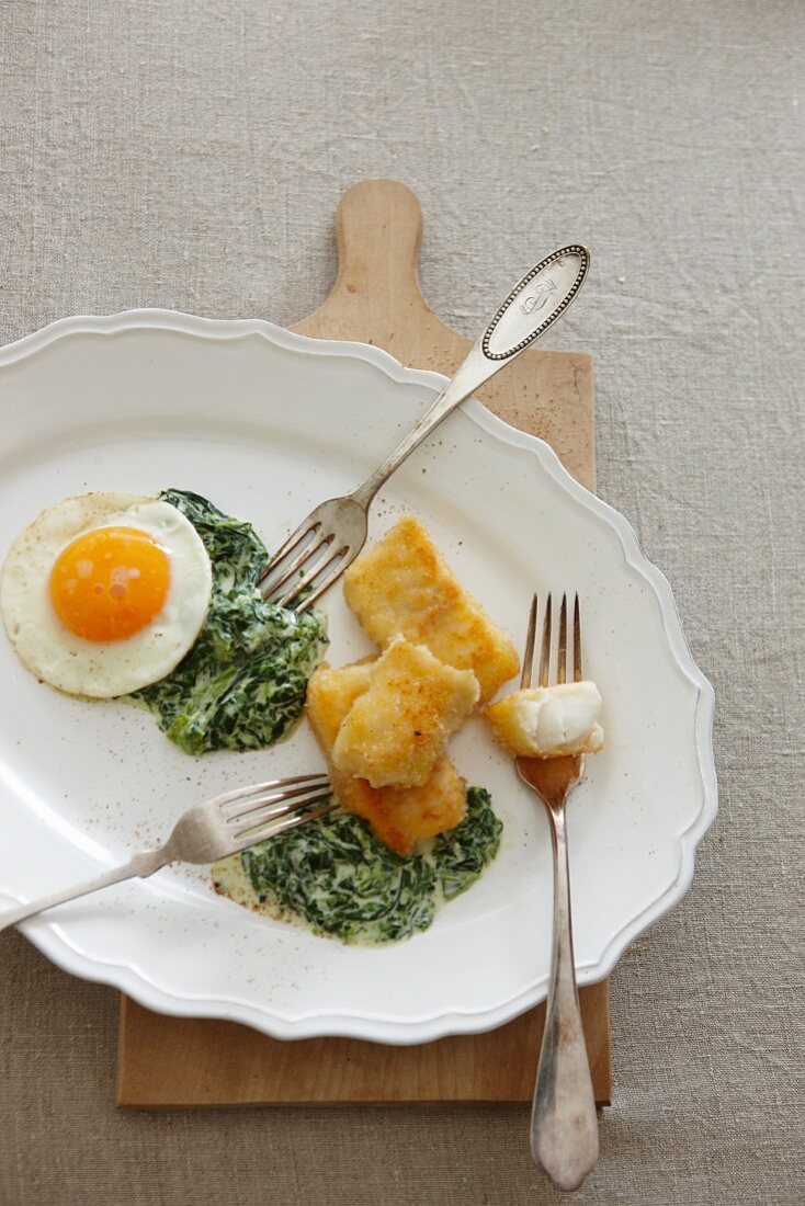 Fish fingers with creamy spinach and a fried egg