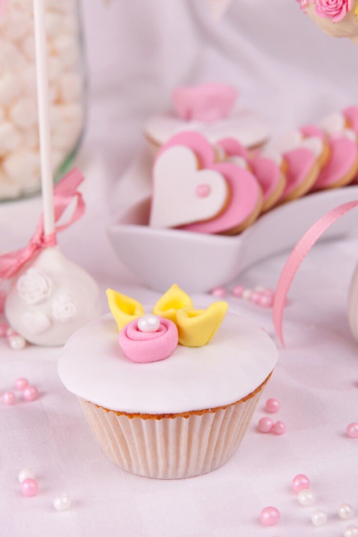 Cupcake mit weisser Glasur, Zuckerrose und Perlen