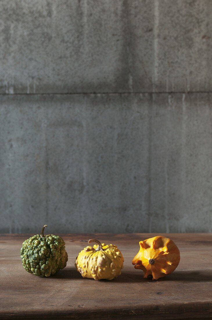 Three ornamental squashes on a wooden table
