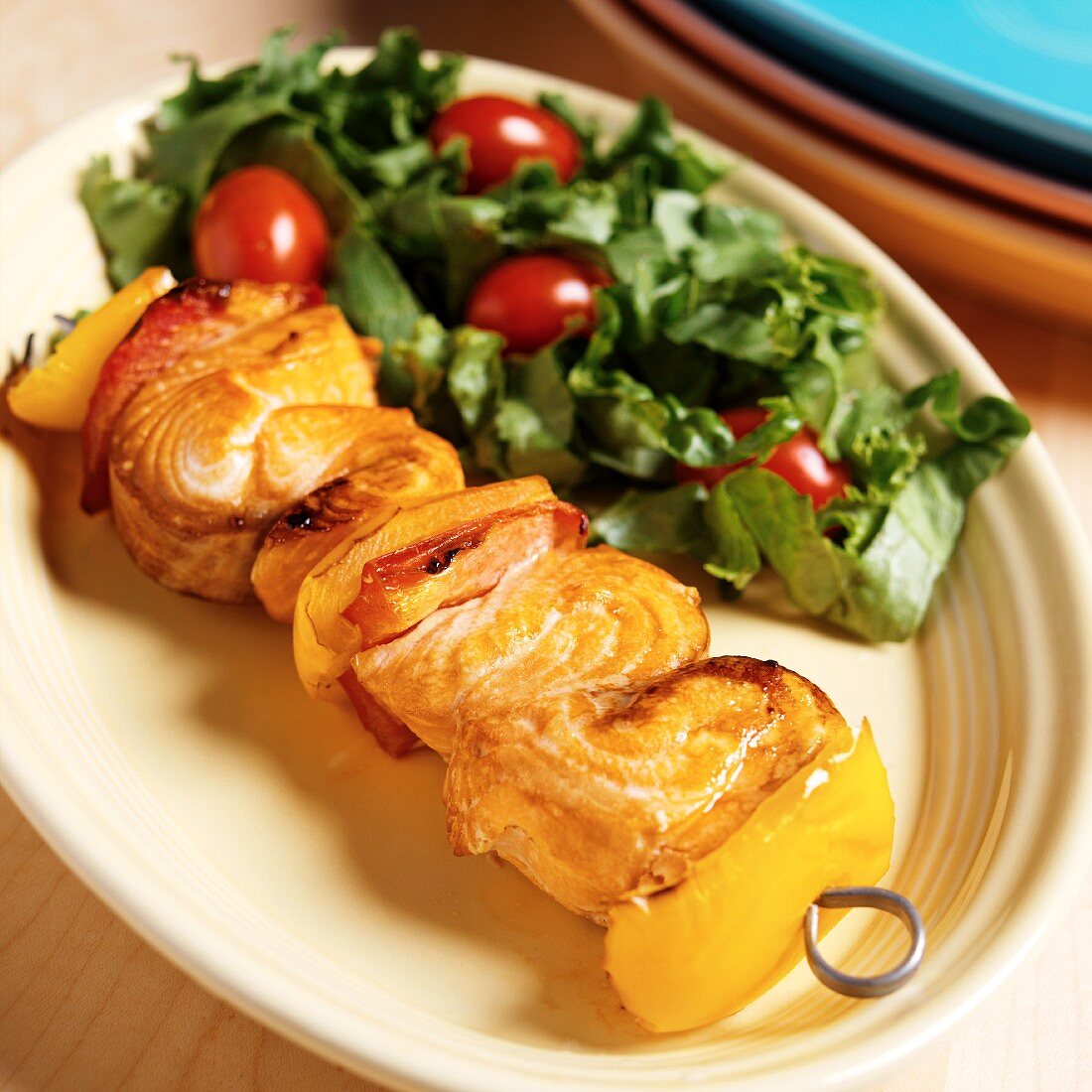 Salmon Kabob Red and Yellow Bell Peppers on a Metal Skewer; Side Salad