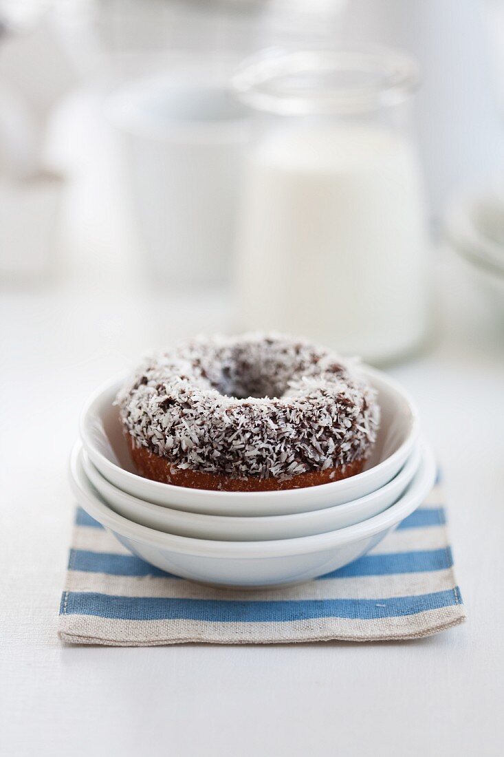 A doughnut with coconut flakes in a stack of bowls