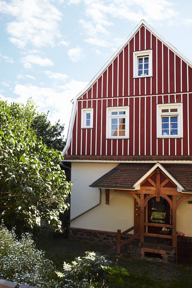 Former school house with red and white striped, wood-clad upper storey and porch