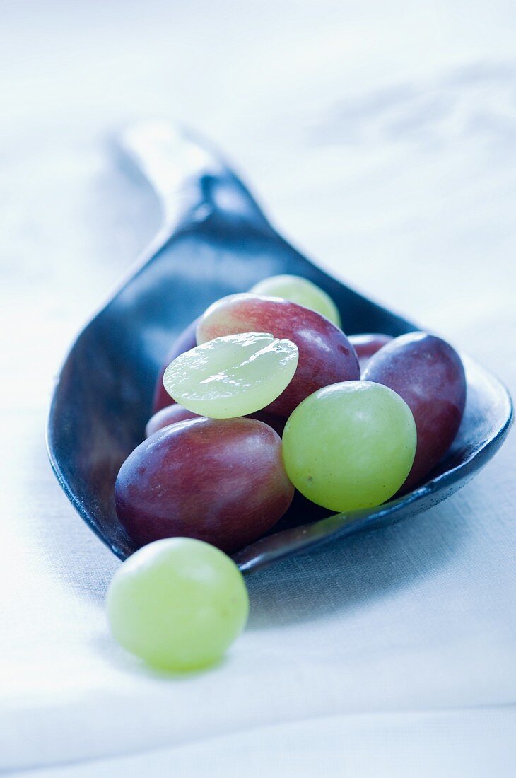 Red and green grapes on a wooden spoon