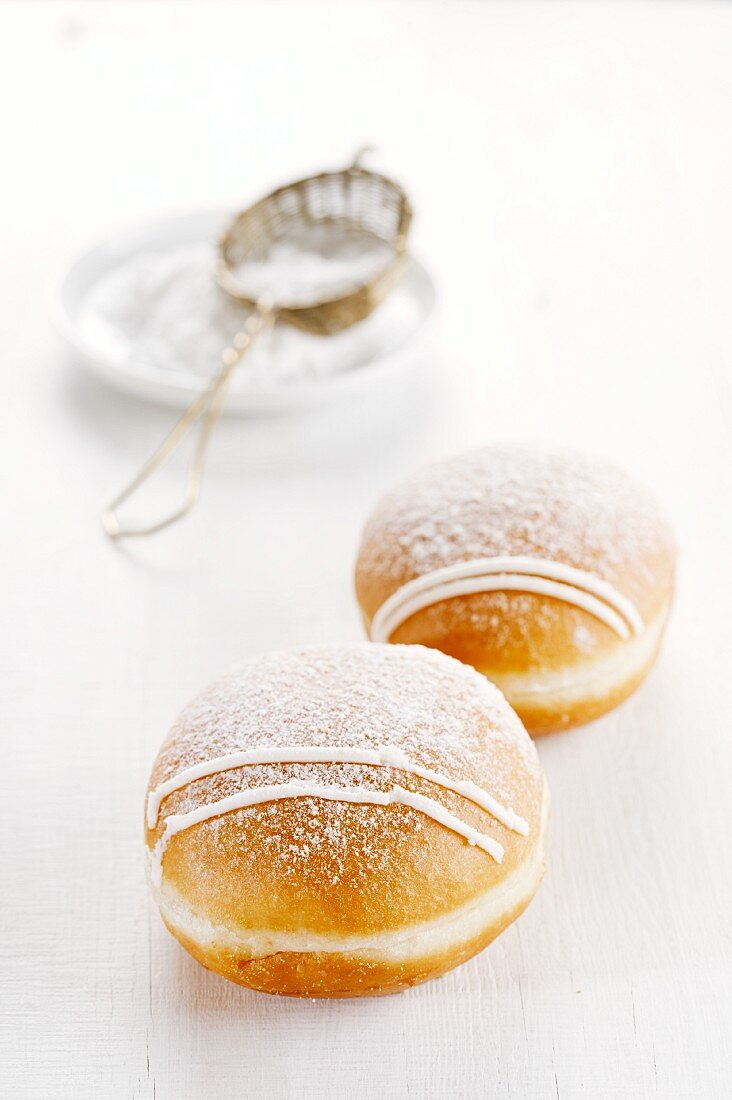 Two doughnuts dusted with icing sugar