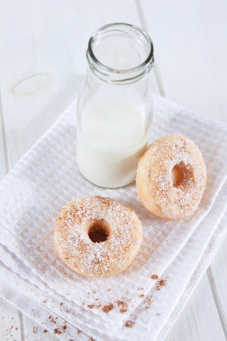 A bottle of milk and doughnuts dusted with cinnamon sugar