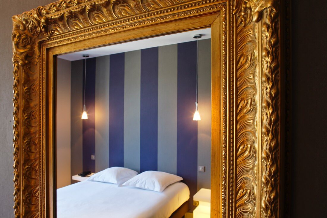 Detail of a baroque wall mirror with a gold frame in a bedroom