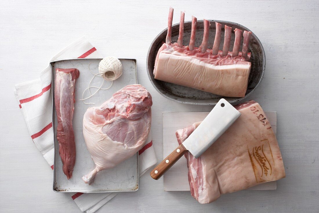 Verschiedene Schweinefleischstücke, Küchengarn und Hackbeil