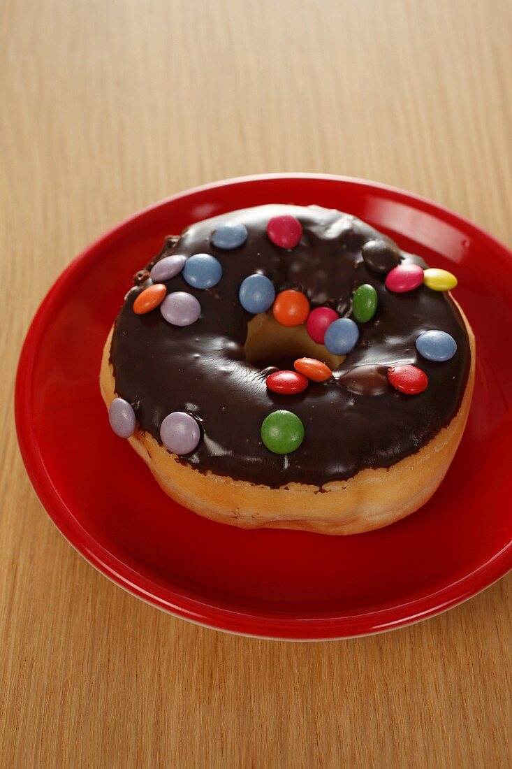 A doughnut with chocolate glaze and colourful chocolate beans