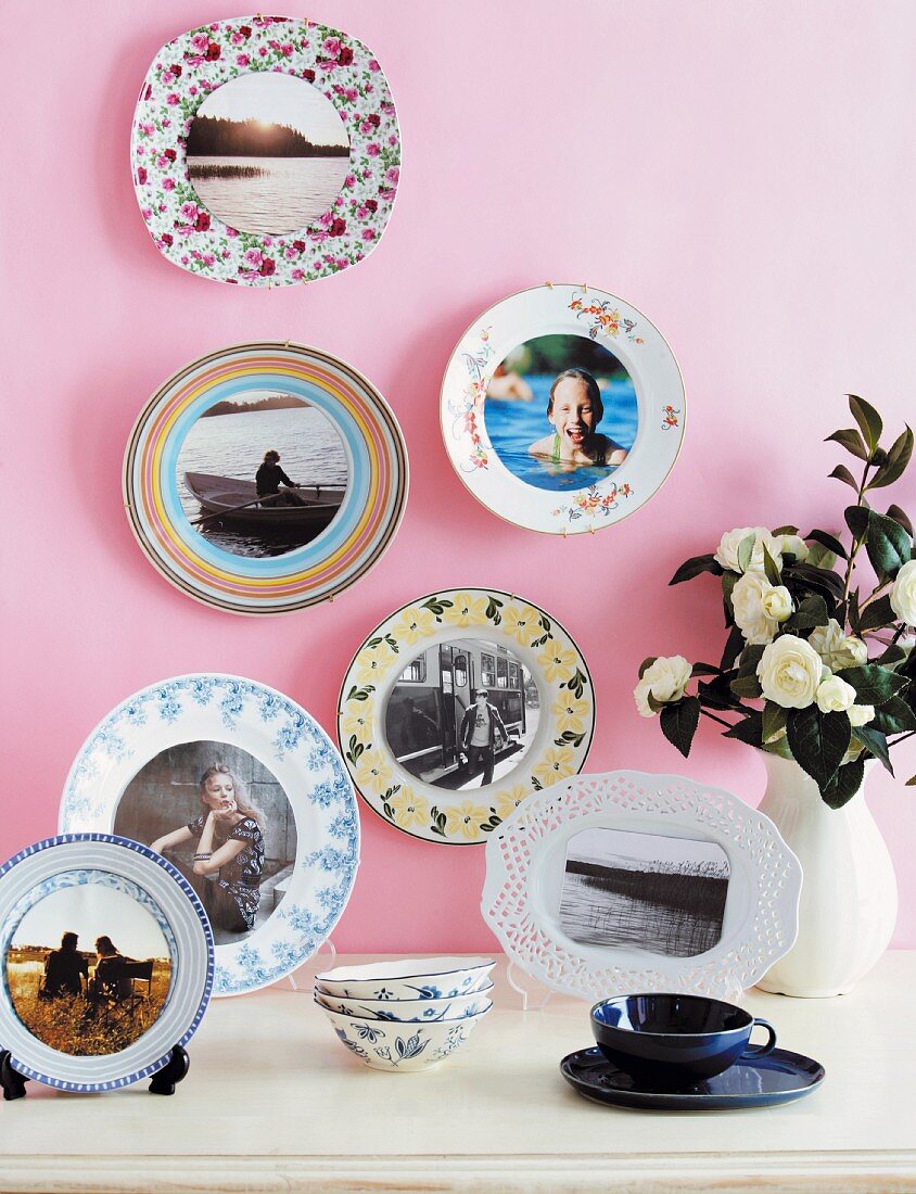 Holiday photos on patterned china plates on pink-painted wall