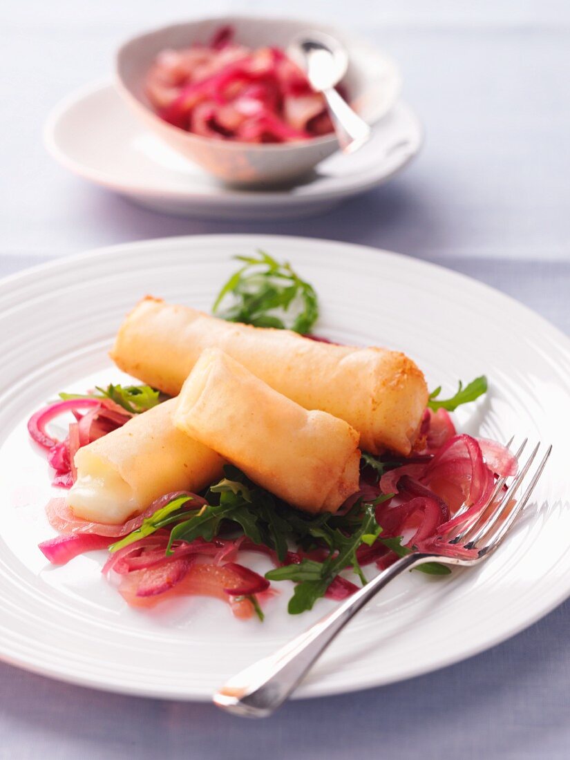 Frittierte Käseröllchen auf Rucola-Zwiebel-Salat