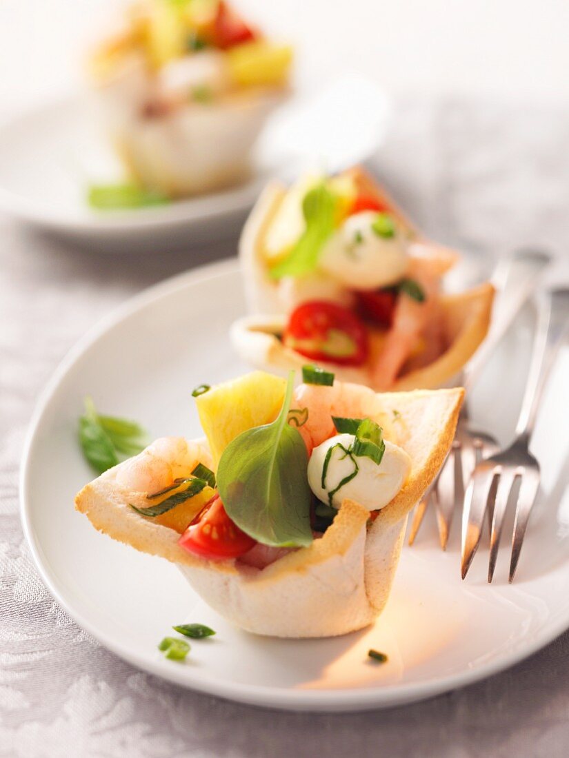 Pastry dishes filled with prawns, tomatoes, mozzarella and basil