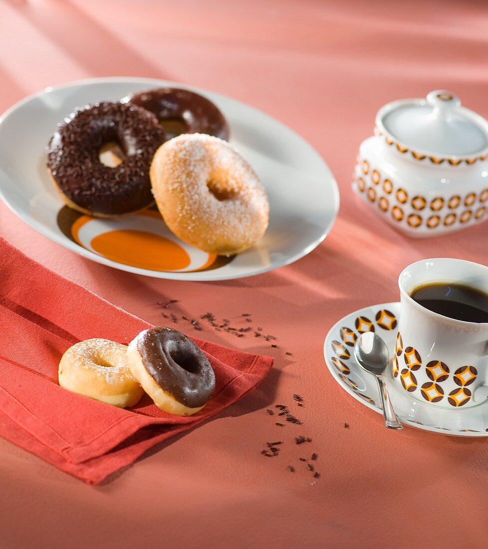 Doughnuts mit Zucker und mit Schokoglasur und eine Tasse Kaffee