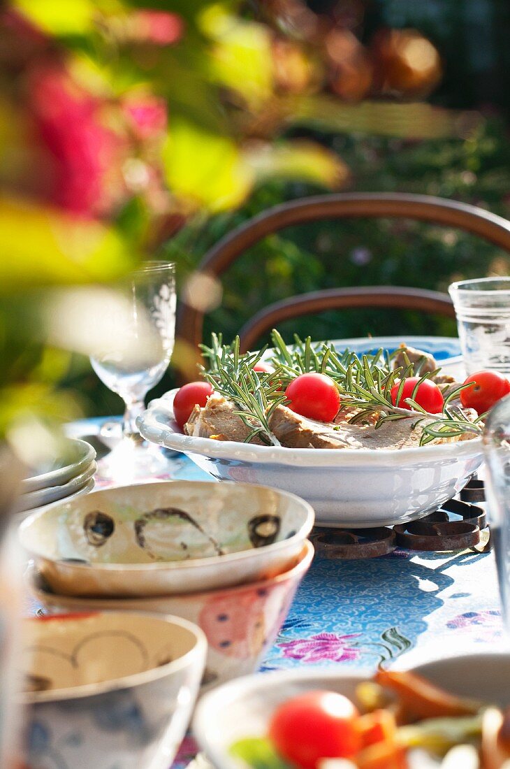 Pork chops with rosemary and cherry tomatoes on a summery table
