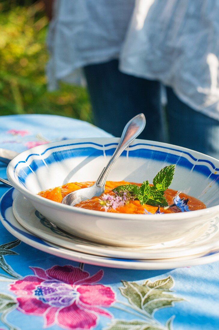 Pepper soup with edible flowers on a summery table