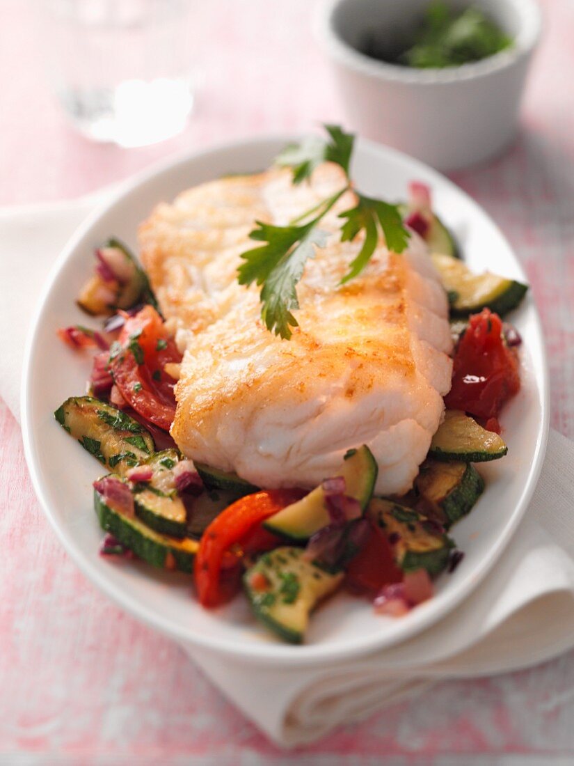 Fish fillet on a bed of courgette and tomatoes