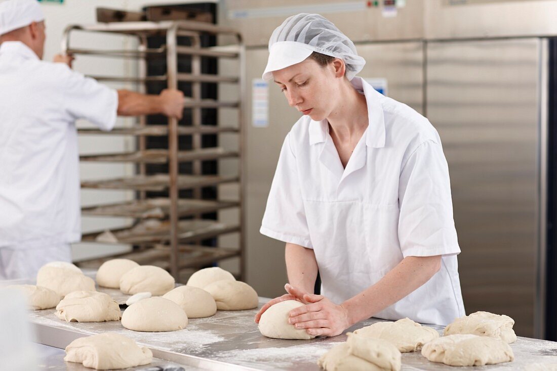 Frau formt Brotlaibe in Bäckerei