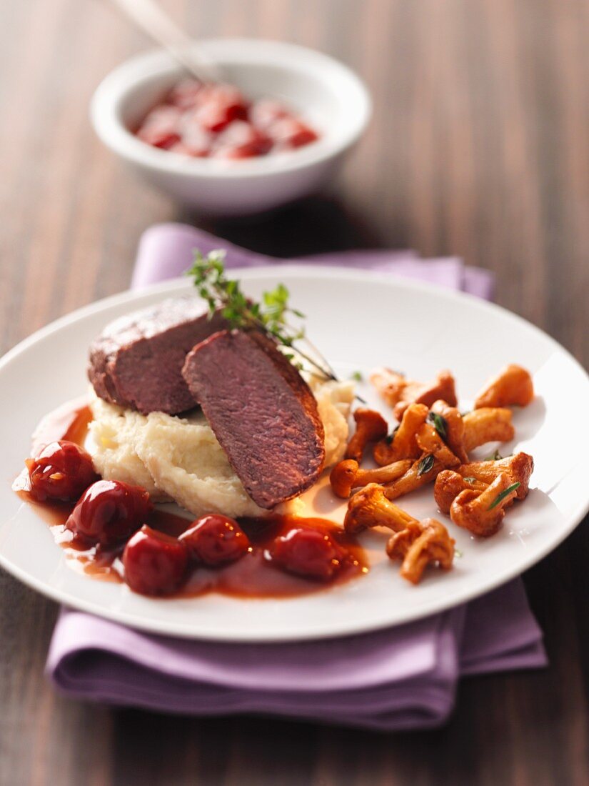 Venison steak on apple mashed potatoes with cherry sauce and chanterelle mushrooms