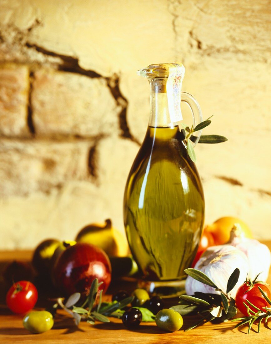 A carafe of olive oil with olives and tomatoes