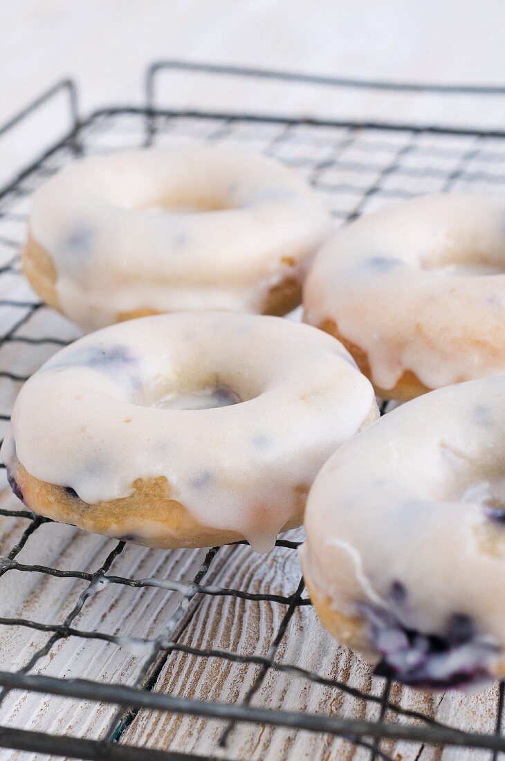 Gebackene Blaubeer-Doughnuts mit Zuckerglasur auf einem Kuchengitter