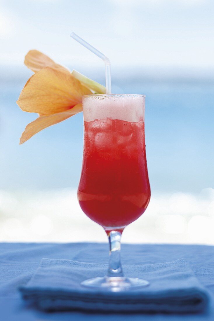 A cocktail on the beach, decorated with a flower