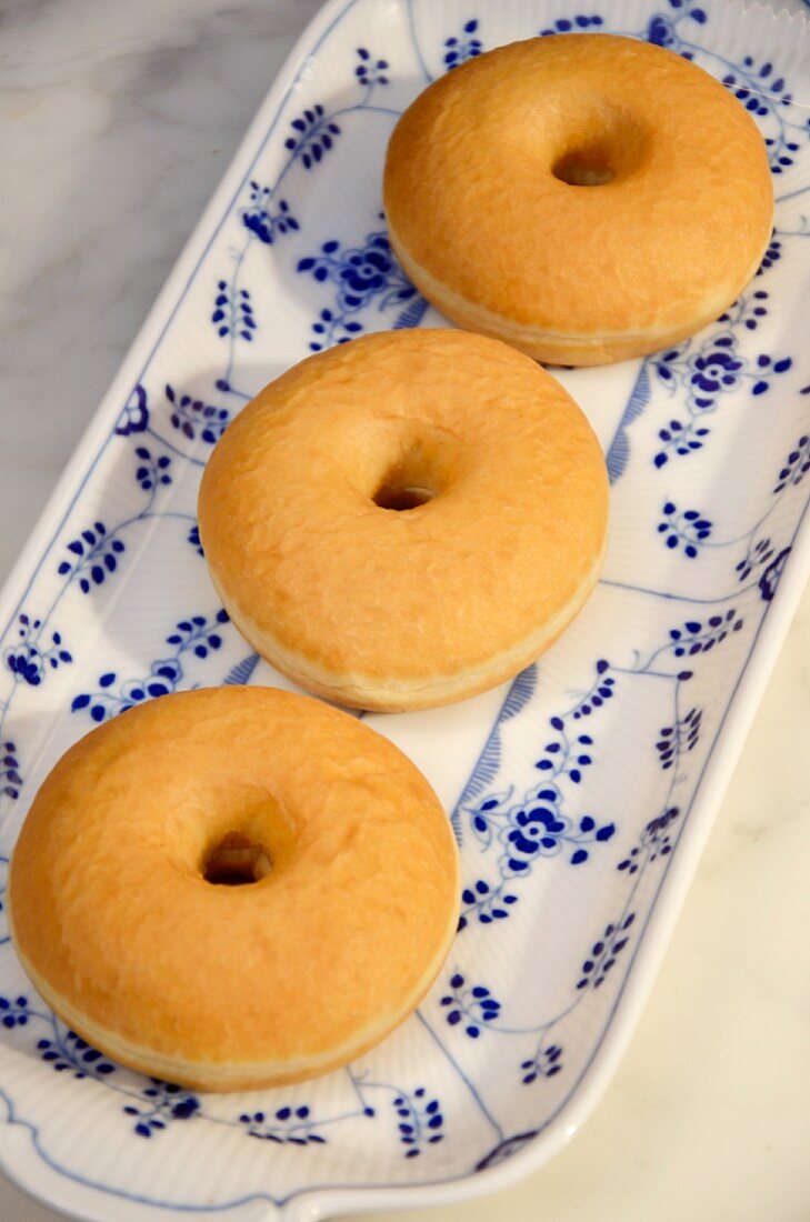 Three doughnuts on a blue and white plate