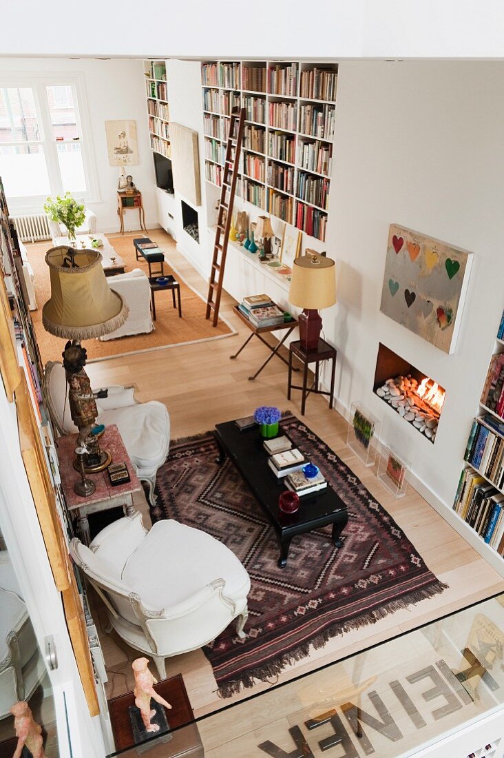 View of an open living room with bookshelves, fireplace and Morrocon carpet