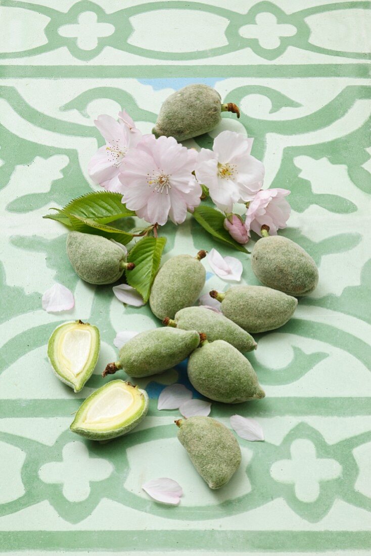 Green almonds and almond flowers on a ceramic surface