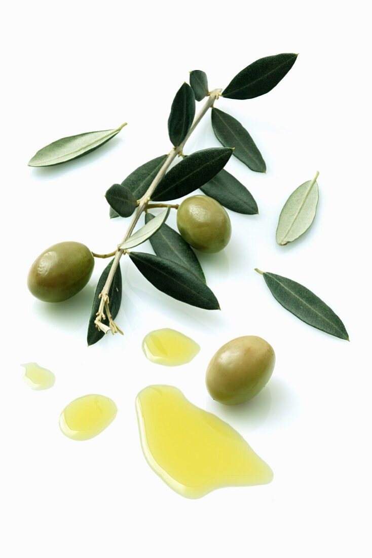 Oivenzweig mit Oliven, daneben ein Klecks Olivenöl