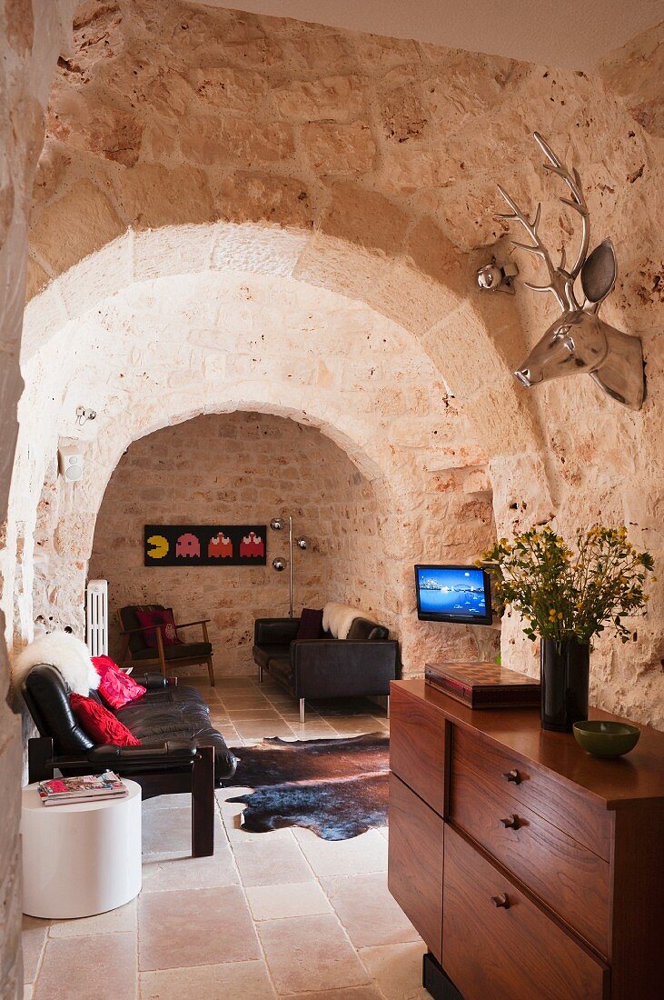 Graham and Green deer head above a sideboard and leather sofa in a the living room of a trullo