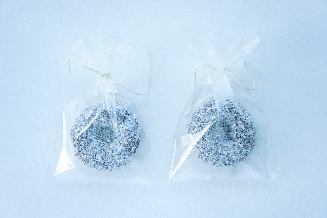 Two doughnuts with chocolate glaze and grated coconut in cellophane bags