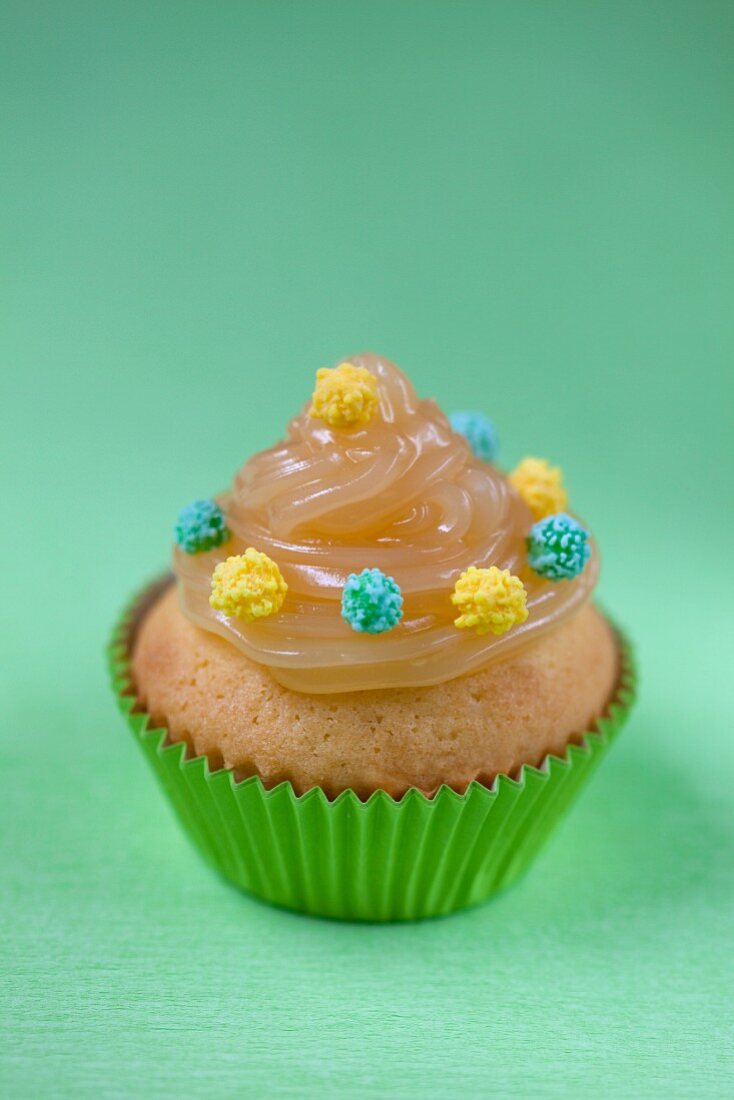 A cupcake decorated with lemon curd and sugar pearls