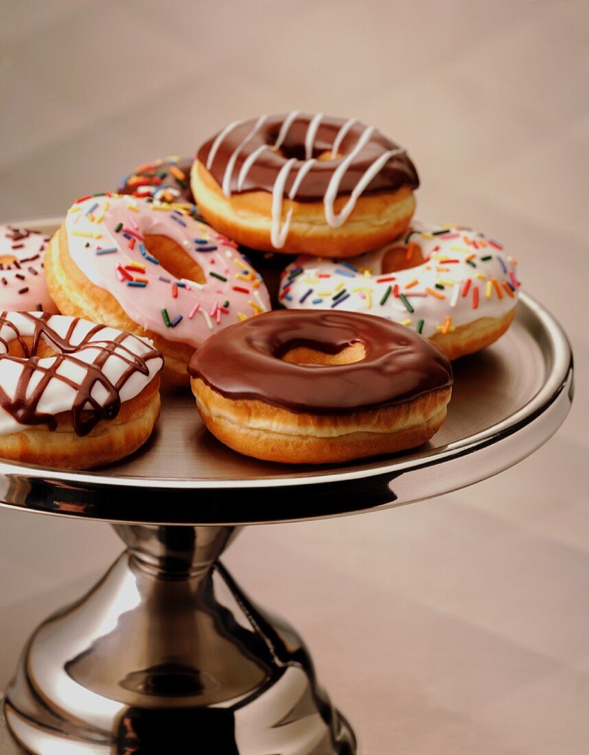 Doughnuts mit Schoko- und mit Zuckerglasur auf einem silbernen Kuchenständer