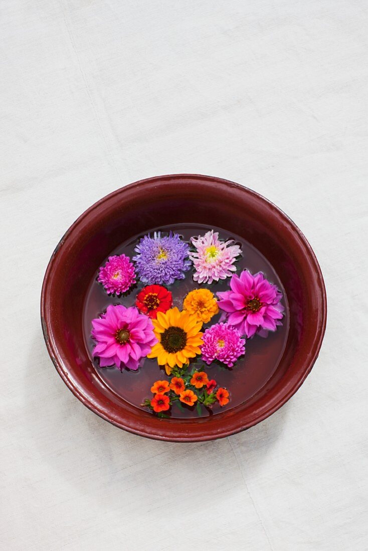 Assorted flowers (dahlia, zinnias, asters, sunflowers) in an old bowl with water