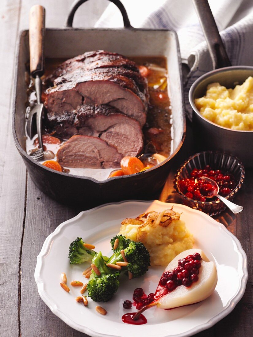Roast wild boar with mashed potatoes, broccoli and lingonberry pears