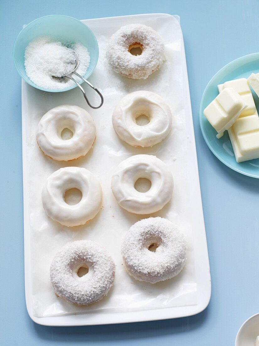 White Chocolate and Coconut Covered Doughnuts; Bowl of Coconut and Chunks of White Chocolate