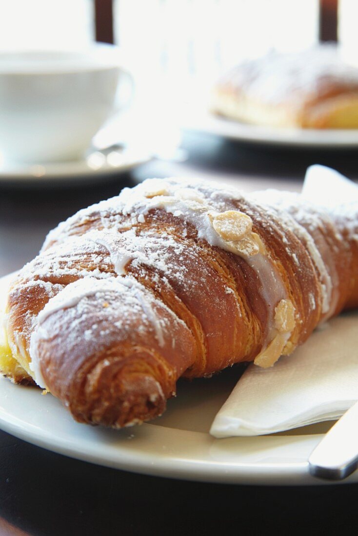 An almond croissant dusted with icing sugar