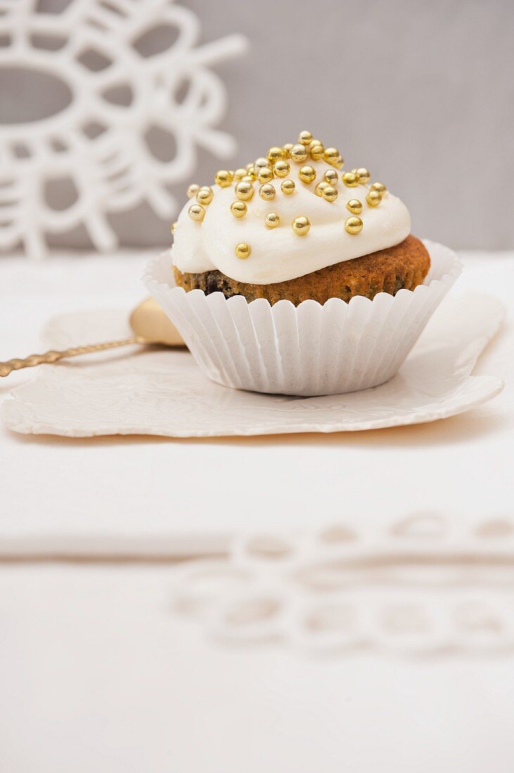 A wintry cupcake decorated with frosting and golden sugar balls