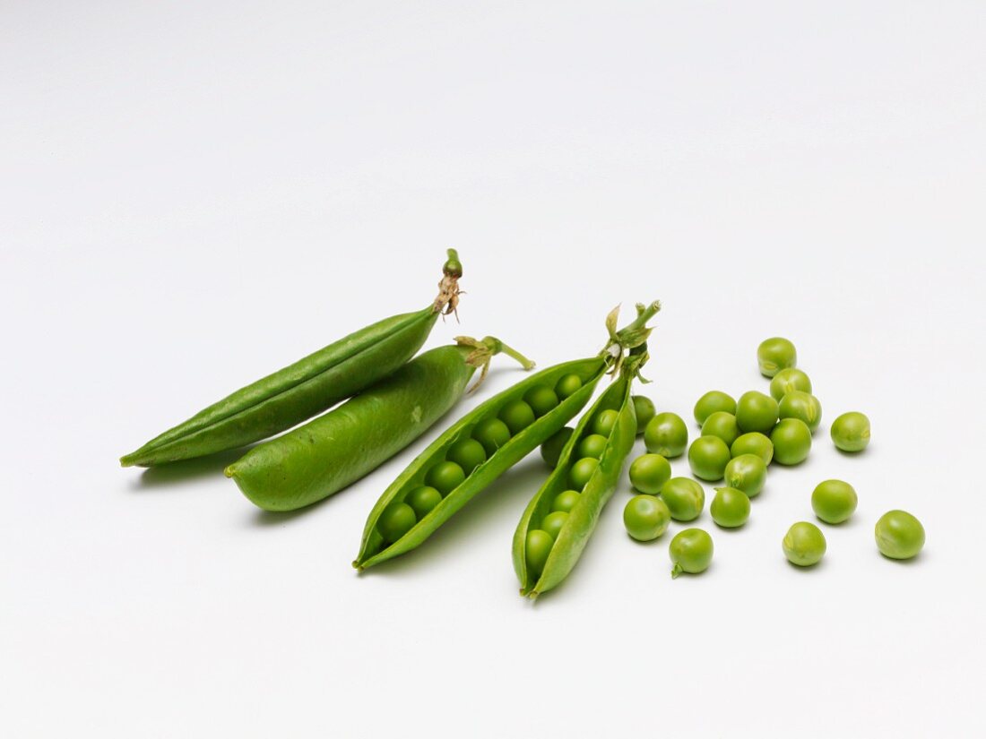 Four pea pods on a white surface