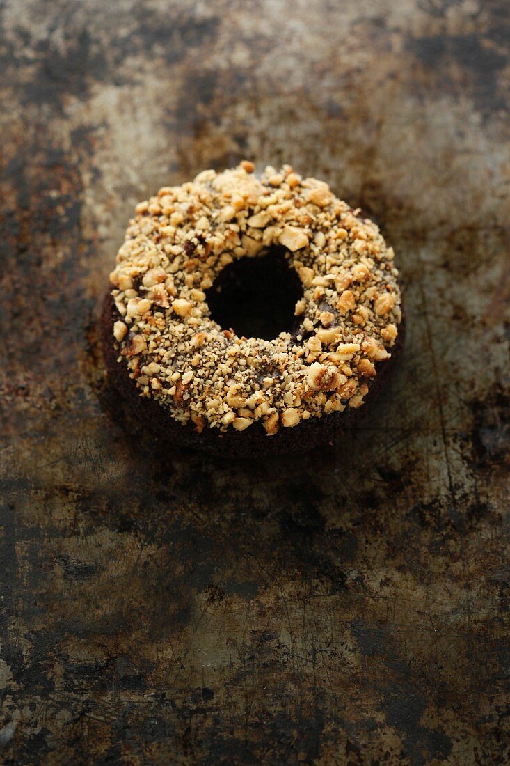 A chocolate and banana doughnut topped with nuts