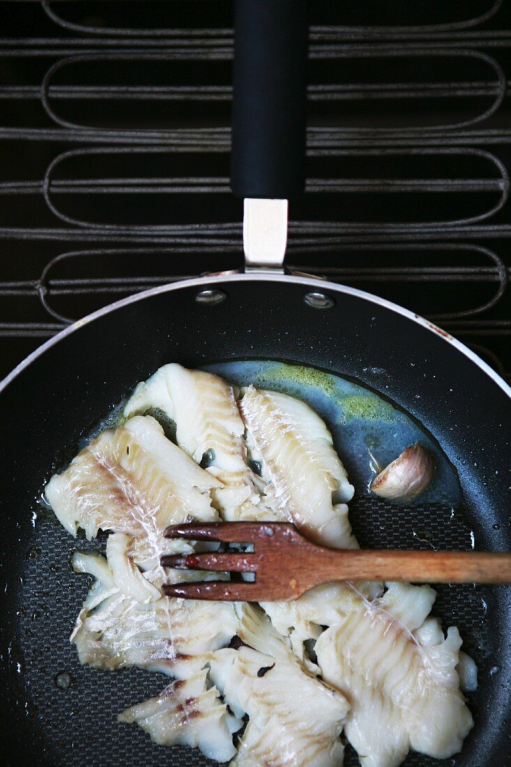 Fish fillet and garlic being fried